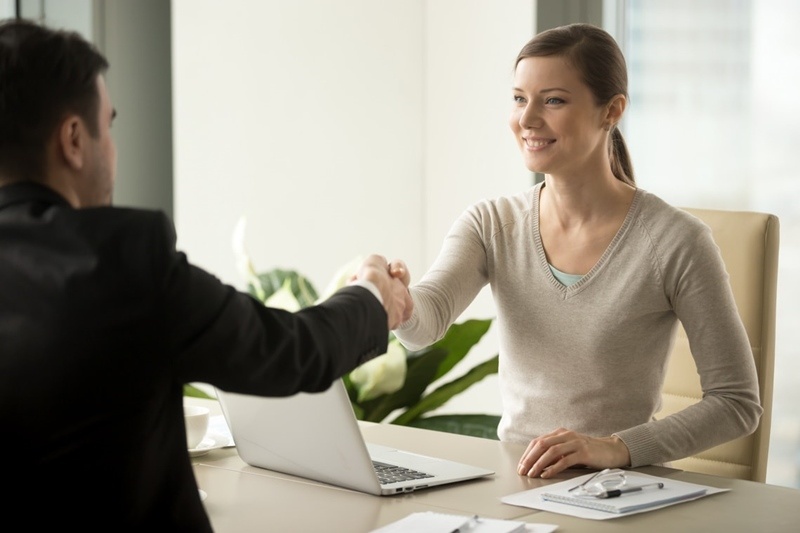 smiling female company leader welcoming with handshake male business partner before or after busines